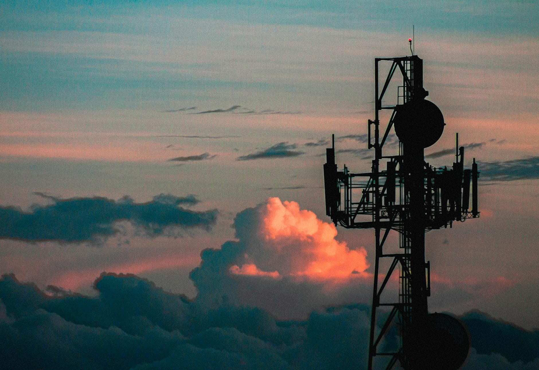 A communication tower silhouette against a colorful sky with vibrant sunset clouds.